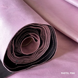 Puede incluir: Un rollo de tela rosa pastel, bien enrollado y listo para ser utilizado en proyectos de costura o manualidades.