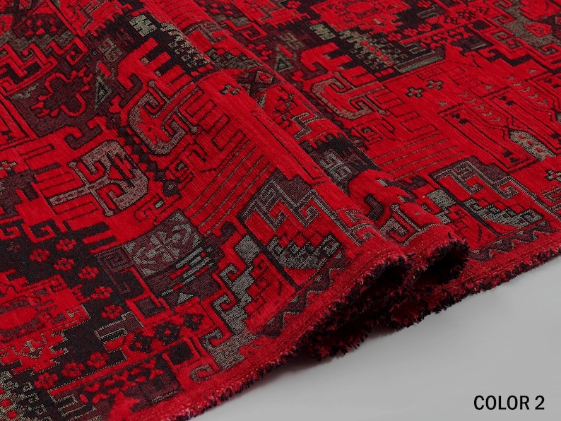 May include: A vibrant red fabric featuring a complex, repeating geometric pattern in black and dark gray. The textile has a textured, woven appearance with visible fibers along the folded edge and the text COLOR 2 in the bottom corner.