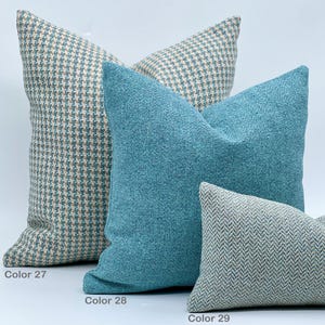 Puede incluir: Tres almohadas decorativas en varios patrones y colores. La almohada de abajo es un patr&oacute;n de espiga verde claro y blanco. La almohada del medio es azul turquesa s&oacute;lido. La almohada de arriba es un patr&oacute;n de cuadros vichy azul claro y beige. Las almohadas est&aacute;n etiquetadas como "Color 27", "Color 28" y "Color 29".