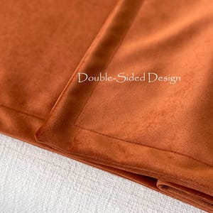 Peut inclure: Gros plan sur un tissu orange br&ucirc;l&eacute; pli&eacute;, recto-verso. Le tissu a une texture douce et velout&eacute;e et une bordure cousue. Le texte "Double-Sided Design" est visible en haut &agrave; droite.