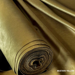 Puede incluir: Un rollo de tela de terciopelo amarillo mostaza. La tela es suave y lujosa, con un brillo sutil.