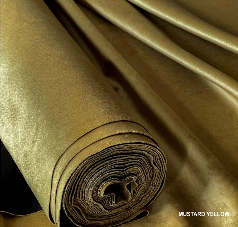 Puede incluir: Un rollo de tela de terciopelo amarillo mostaza. La tela es suave y lujosa, con un brillo sutil.