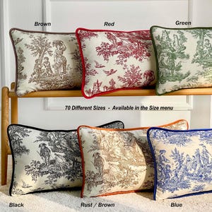 K&ouml;nnte beinhalten: Dekorative Zierkissen in verschiedenen Farben, darunter Braun, Rot, Gr&uuml;n, Schwarz, Rostbraun und Blau. Jedes Kissen zeigt ein Toile-de-Jouy-Muster mit einem kontrastierenden Rand. Der Text "70 Different Sizes - Available in the Size menu" ist zu sehen.