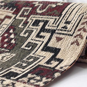 May include: A woven textile fabric featuring a complex geometric pattern in deep red, black, and cream colors. The material has a textured surface with visible interlaced threads forming intricate angular shapes and repeating motifs.