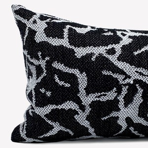 May include: Black and white patterned throw pillow with a geometric design. The pillow is made of a woven fabric and has a rectangular shape.