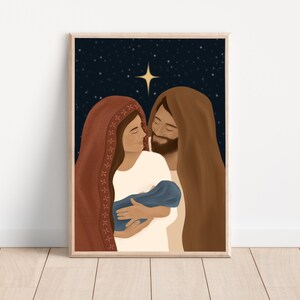 Puede incluir: Una impresi&oacute;n art&iacute;stica enmarcada que representa una escena religiosa. La ilustraci&oacute;n muestra a una mujer con un tocado rojo y un hombre con un tocado marr&oacute;n, mirando a un beb&eacute; envuelto en azul. Una estrella brilla en el fondo azul oscuro.