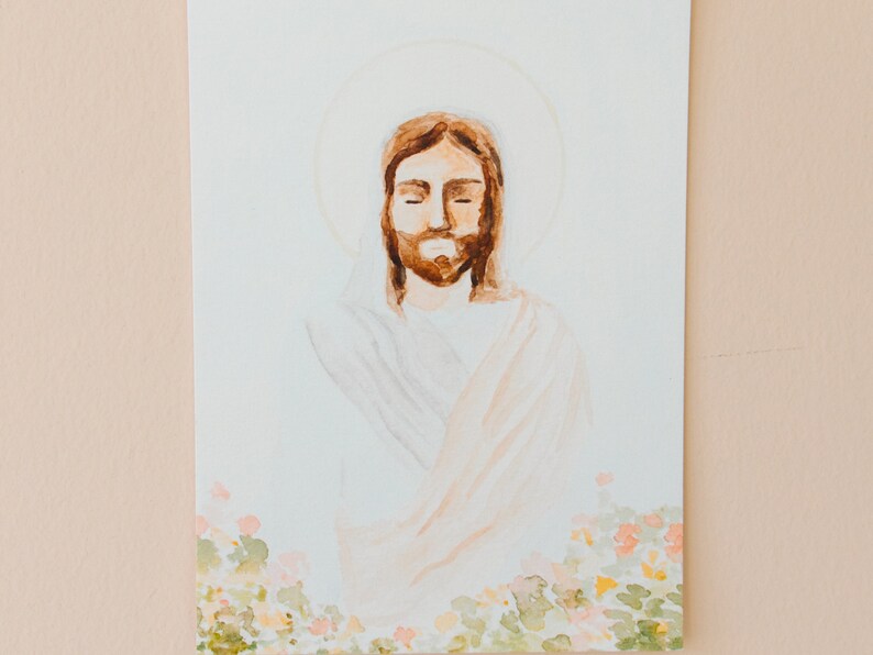 May include: Watercolour painting of a figure with closed eyes, brown hair, and a beard, surrounded by a halo. The figure is wearing a white robe with peach-coloured accents. The bottom of the painting features a floral border with green and pink hues.