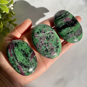 May include: Three green, black, and pink gemstone tumbled stones. The stones are smooth and polished, and they have a variety of patterns and colors.