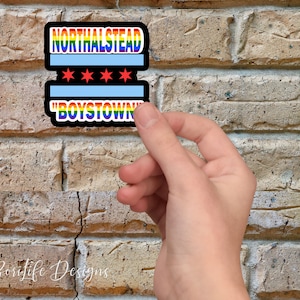 May include: A sticker with a rainbow design and the text "Northalstead" and "Boystown" on a brick wall.
