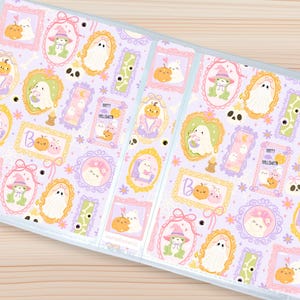 Puede incluir: Una cubierta de agenda de color lila claro con un patrón repetido de ilustraciones de Halloween enmarcadas. Las ilustraciones incluyen fantasmas, calabazas, ranas y el texto "Happy Halloween". Los marcos son de varios colores pastel.