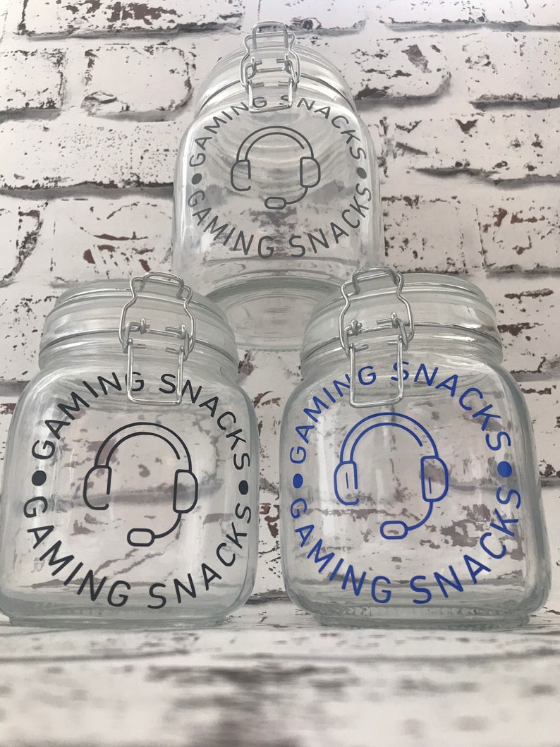 May include: Three clear glass jars with black lids and labels that say "Gaming Snacks" with a blue headset icon.