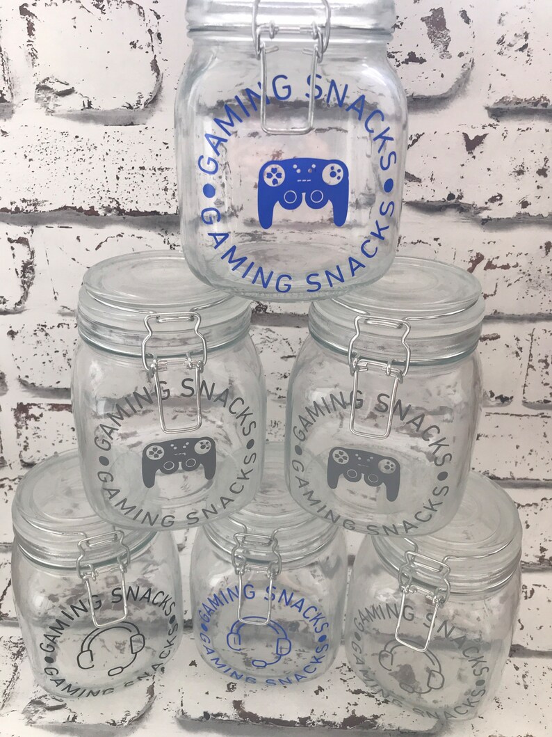 May include: Five clear glass jars with airtight lids. Each jar has a blue and gray sticker with the text "Gaming Snacks" and a graphic of a video game controller or headphones.