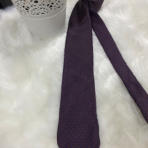 以下が含まれることがあります： 赤と青の幾何学模様の入った濃い青色のネクタイ