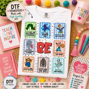 May include: A white t-shirt featuring a graphic print with nine colorful rectangular frames, each containing a character and text such as Calm Like The Very Hungry Caterpillar, Kind Like Rainbow Fish, and Creative Like Pigeon, with the word BE in red.
