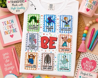 Puede incluir: Una camiseta blanca con un estampado gráfico de nueve marcos rectangulares coloridos, cada uno con un personaje y texto como Calm Like The Very Hungry Caterpillar, Kind Like Rainbow Fish y Creative Like Pigeon, con la palabra BE en rojo.