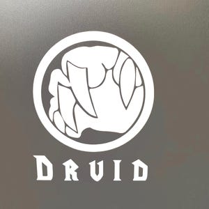 May include: White vinyl sticker with a circle containing a white silhouette of a claw with fangs. The word "DRUID" is written in white below the circle.