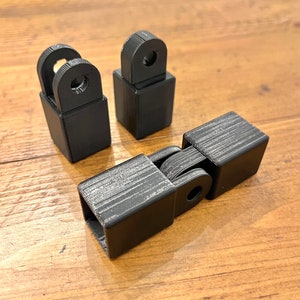 May include: Three black plastic connectors with a square shape and a round hole in the center. The connectors are designed to be joined together.