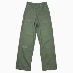 May include: Olive green utility pants featuring a high-waisted design with a button fly closure. These trousers include two large rectangular patch pockets on the front, vertical seam detailing along the legs, and a straight-leg silhouette.