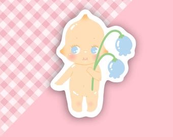 Puede incluir: Una pegatina de un bebé de dibujos animados sosteniendo un ramo de flores azules con tallos verdes. El bebé tiene un tono de piel amarillo claro, ojos azules y un rubor rosado en las mejillas.