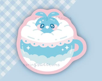 Peut inclure: Un autocollant représentant un lapin bleu dans une tasse bleue avec des nuages blancs et des étoiles. La tasse est bleu clair avec une bordure rose. Le texte "springsweetums" est visible sur l'autocollant.