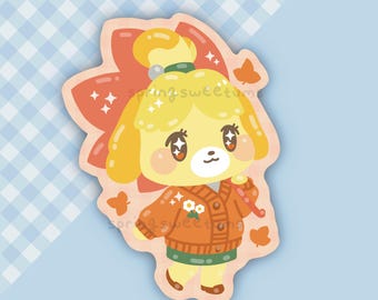 Peut inclure: Un autocollant représentant un personnage de dessin animé avec une fourrure jaune, vêtu d'un pull orange avec des détails de fleurs blanches et une jupe verte. Le personnage a un nœud rouge et est entouré de feuilles et de papillons oranges. Le texte "springsweetums" est visible.