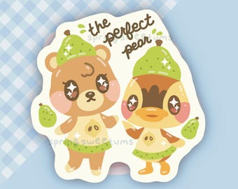 Peut inclure: Un autocollant découpé représentant un ours brun et un canard jaune, portant tous deux des chapeaux en forme de poire verte et des tenues assorties. Le texte "the perfect pear" est écrit en brun au-dessus des personnages aux yeux étoilés.