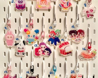 Peut inclure: Collection de porte-clés en acrylique colorés représentant divers personnages et motifs de dessins animés. Comprend des porte-clés avec un chien, un chat, un hibou et des personnages d'émissions animées populaires. Chaque porte-clés est attaché à un fermoir en métal et à une lanière.