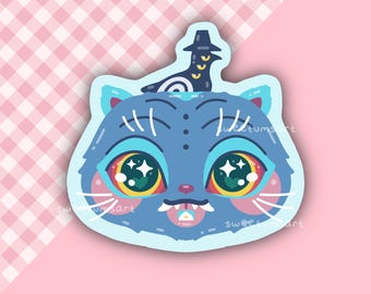 Peut inclure: Un autocollant fantaisiste représentant un chat bleu avec de grands yeux colorés et un chapeau. Le chat a des moustaches blanches et une petite langue rose. Fond rose à carreaux blancs.