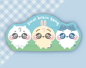 Peut inclure: Un autocollant avec trois personnages de dessins animés : un ours blanc, un lapin jaune et un chat blanc avec un nœud bleu. Ils ont de grands yeux étincelants et des joues roses. Le texte "smol brain gang" est au-dessus.