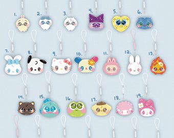 Peut inclure: Collection de 26 breloques de téléphone en acrylique, chacune mesurant 2,5 à 3,2 cm, avec des lanières blanches tressées. Les motifs incluent divers personnages de dessins animés et illustrations mignonnes. Le texte "springsweetums.com" est visible.