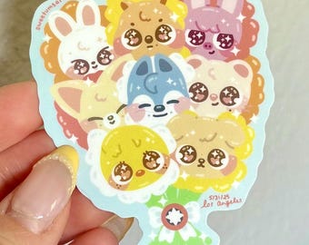 Peut inclure: Un autocollant représentant un bouquet de visages d'animaux de dessins animés, dont un lapin, un ours, un renard et un poussin. Les animaux ont de grands yeux expressifs et sont entourés d'un motif floral. Le texte "5/31/25 Los Angeles" et "sweetumsart" est présent.