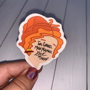 May include: A sticker featuring a cartoon illustration of a woman with orange hair. The sticker has the text "Take Chances, Make Mistakes, Get Messy" on it.