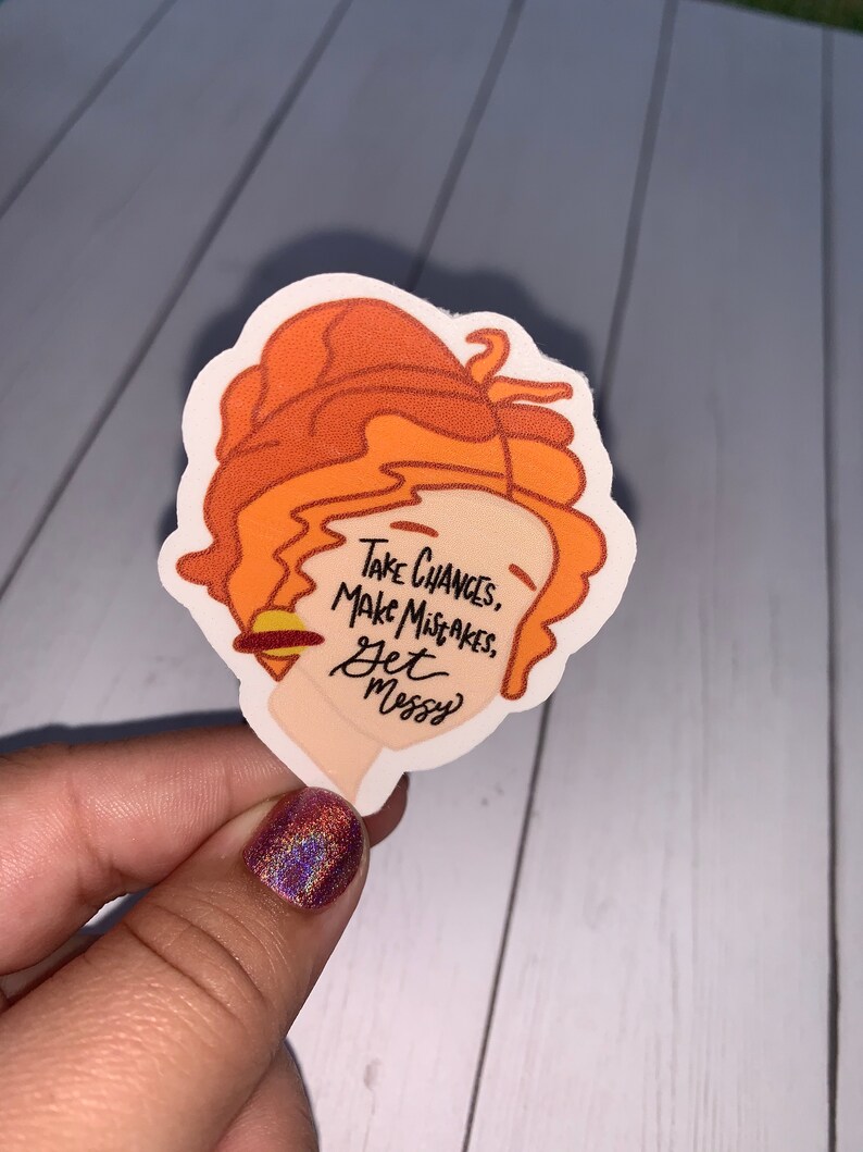 May include: A sticker featuring a cartoon illustration of a woman with orange hair. The sticker has the text "Take Chances, Make Mistakes, Get Messy" on it.