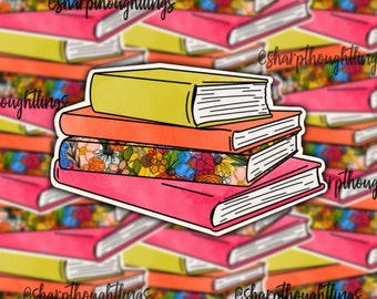 May include: A stack of four books with colorful floral patterned paper on the cover of the third book. The top book is yellow, the second book is orange, the third book is pink with floral paper, and the bottom book is pink.