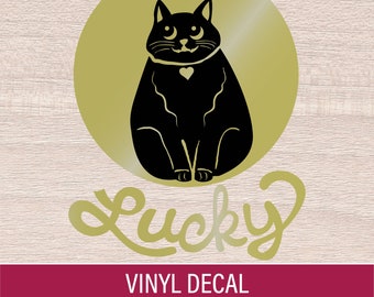 Könnte beinhalten: Schwarze Katzen-Silhouette mit herzförmigem Kragen, vor einem goldenen Kreis. Das Wort "Lucky" ist in einer Schreibschrift unter der Katze geschrieben. Das Bild enthält den Text "VINYL DECAL" und "MANY COLOR & SIZE OPTIONS".