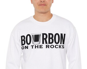 Pode incluir: Camisola branca com texto preto que diz "BOURBON ON THE ROCKS" e uma silhueta preta de um copo de shot com líquido dentro.