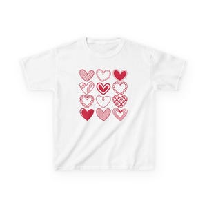 May include: White t-shirt with a red heart design. The hearts are all different shapes and sizes, and some have patterns inside.