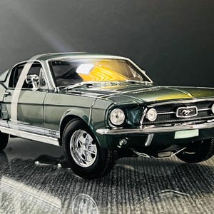 May include: A dark green classic Mustang model car with chrome detailing. The car features a detailed interior, chrome wheels, and a Mustang emblem on the front grille. The model is a detailed replica of a vintage sports car.