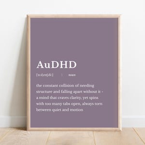 Puede incluir: Un cartel enmarcado con la palabra "AuDHD" en texto blanco sobre un fondo morado. La definición de AuDHD está debajo, describiendo la constante colisión de necesitar estructura y desmoronarse sin ella.