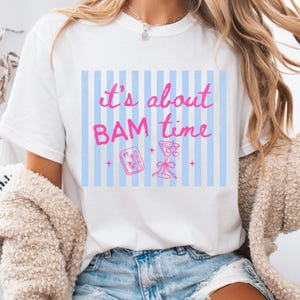 Puede incluir: Camiseta blanca con un gr&aacute;fico rosa y azul que dice "It's about BAM time". El gr&aacute;fico incluye un c&oacute;ctel, un vaporizador de bamb&uacute; y rayas verticales azules. La camiseta est&aacute; hecha de un material suave.