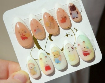 May include: Set of ten false nails with a white base and a clear top coat. Each nail features a different cartoon animal design with pastel colors.