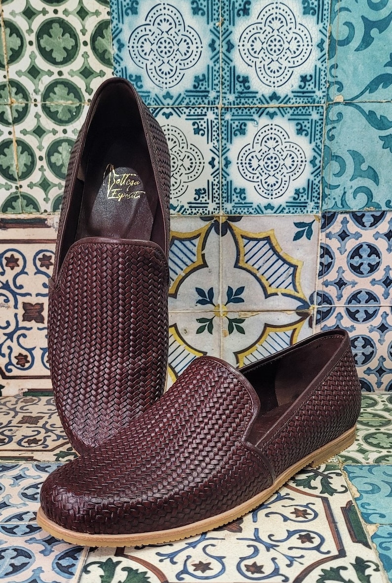 May include: A pair of dark brown woven leather loafers with a brown leather sole. The loafers have a woven pattern and the text "Dolce & Esprite" is visible on the inside of one of the loafers.