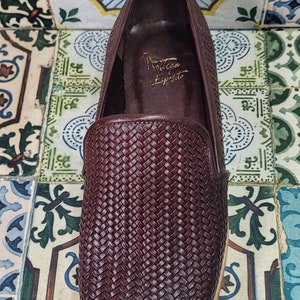 May include: A pair of brown leather woven slip-on shoes with a rounded toe. The shoes have a woven leather upper and a leather sole. The brand name "Soltana Espirit" is written on the inside of the shoe.