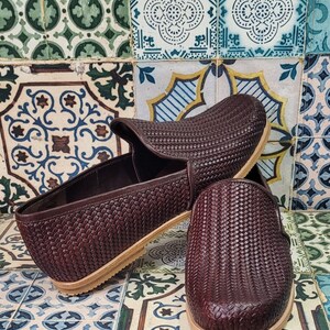 May include: A pair of brown woven leather slip-on shoes with a light brown sole.
