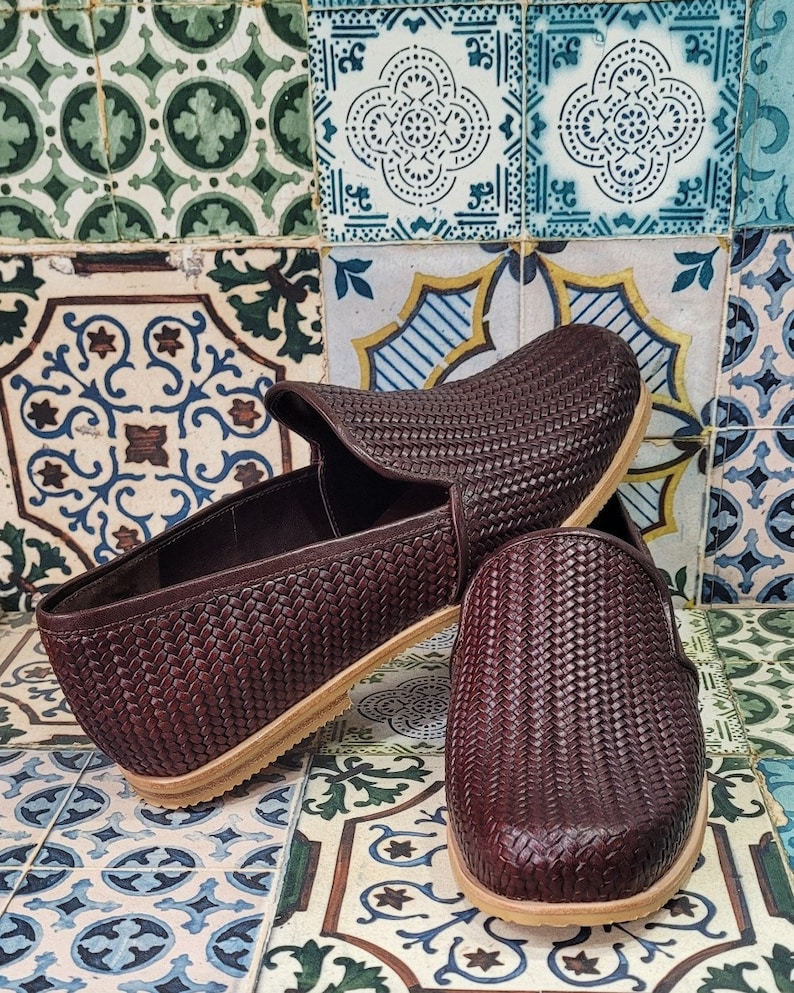 May include: A pair of brown woven leather slip-on shoes with a light brown sole.