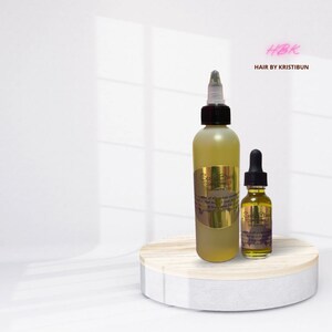 May include: Two bottles of hair growth oil with gold labels and a black cap. The larger bottle is labeled "Scalp Elixir Growth Oil" and the smaller bottle is labeled "Scalp Elixir Serum". The bottles are on a wooden platform. The text "HBK Hair by Kristibun" is in pink at the top of the image.