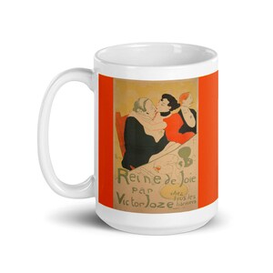 May include: White ceramic mug with a colorful image of a vintage poster for the play "La Reine de Joie" by Victor Joze. The poster features three people in a scene with a red, orange, and yellow color scheme.