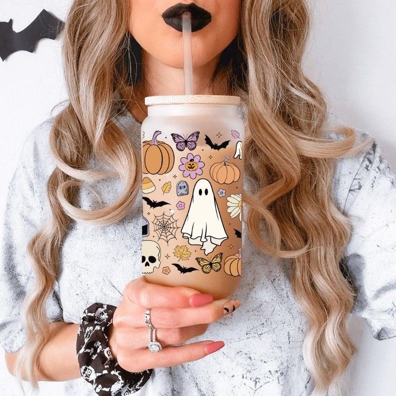 Pu&ograve; includere: Un bicchiere di vetro smerigliato a forma di lattina con un design a tema Halloween. Il design include zucche, farfalle, pipistrelli, un fantasma e una ragnatela. Il bicchiere ha un coperchio di bamb&ugrave; e una cannuccia.