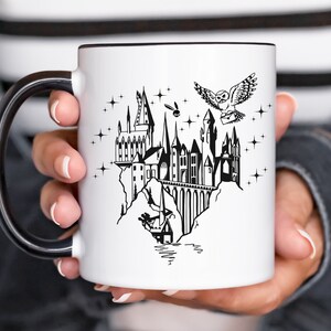 Puede incluir: Taza de cer&aacute;mica blanca con interior y asa negros. La taza presenta una ilustraci&oacute;n negra de un castillo, un b&uacute;ho que lleva una carta y estrellas. El dise&ntilde;o evoca un tema de fantas&iacute;a.