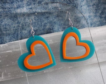 Peut inclure: Une paire de boucles d'oreilles en forme de cœur turquoise et orange avec des crochets argentés.